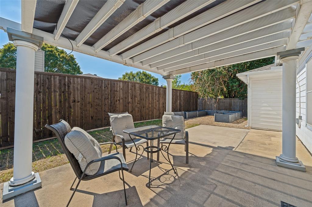 Concrete patio featuring a structural pergola with white columns and a dark stained wood privacy fence
