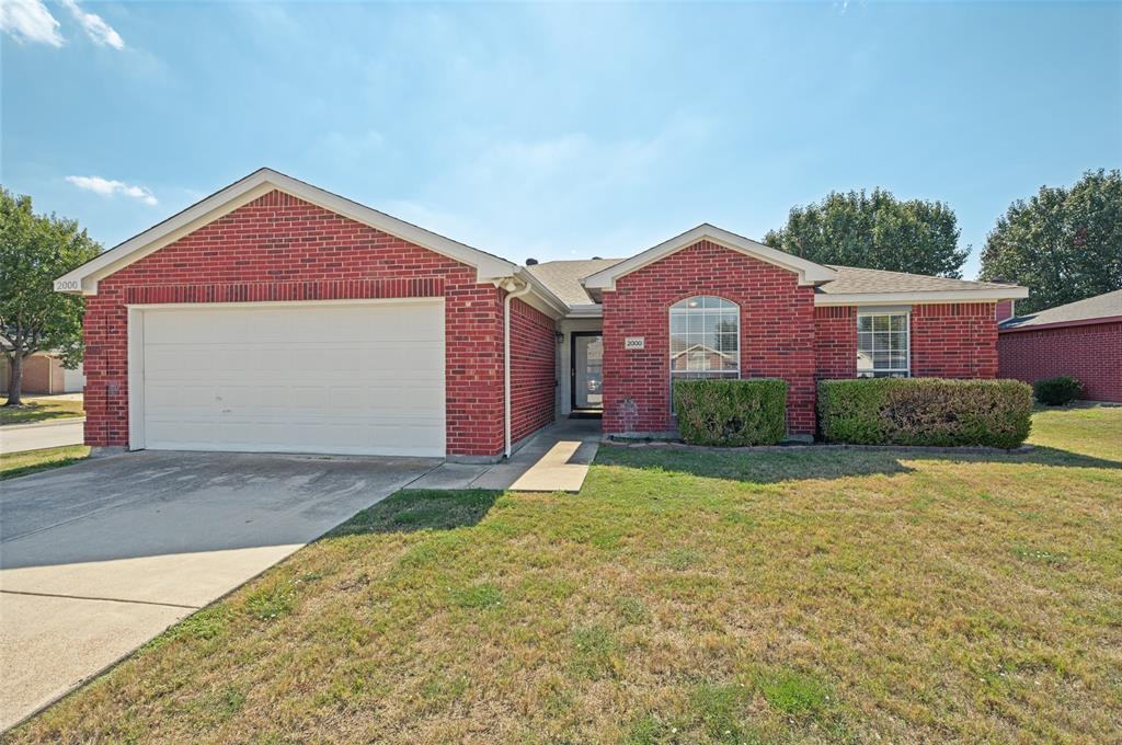 Red brick exterior featuring a front-facing attached garage, arched window detail, concrete driveway, and covered entryway