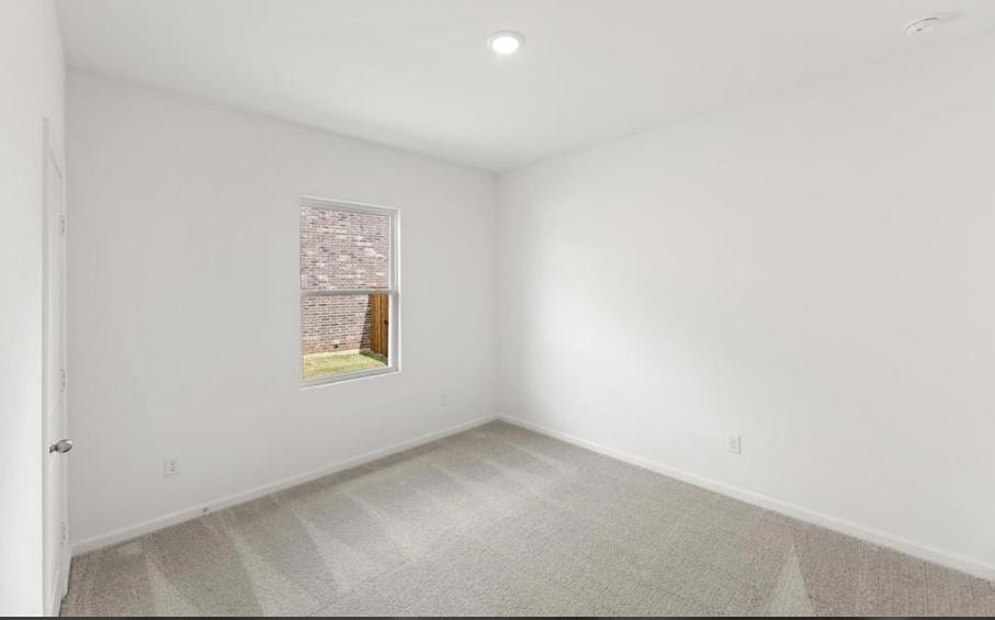 Neutral interior space featuring carpeted flooring, recessed lighting, and a single-pane window