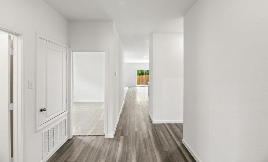 Hallway featuring wood-finish plank flooring, crisp white walls, and a recessed doorway