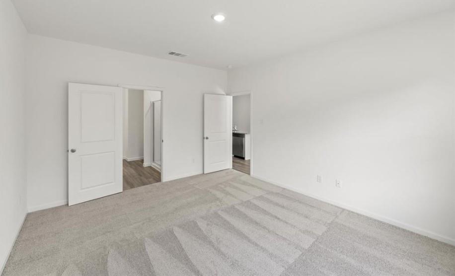 Neutral-toned wall-to-wall carpeting, recessed ceiling lighting, and two-panel interior doors