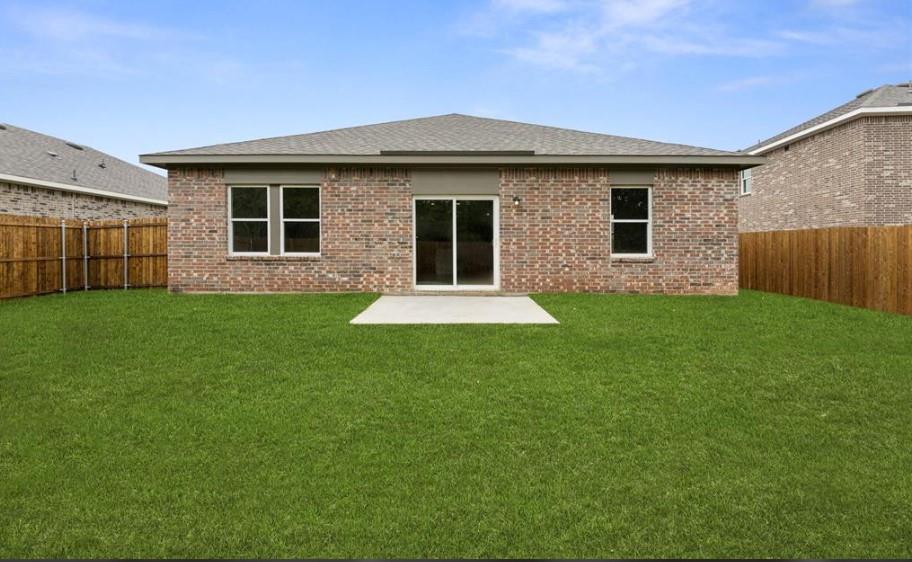 Brick exterior, rear concrete patio, sliding glass doors, and fully enclosed wood fencing