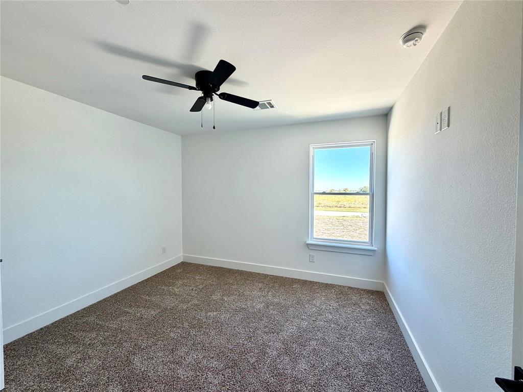 Neutral-toned wall-to-wall carpeting, single-hung window with exterior landscape exposure, matte black ceiling fan, and crisp white wall finish
