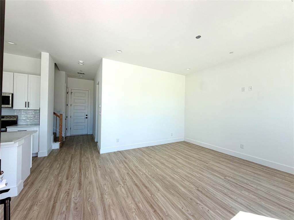 Open-concept interior featuring wood-finish flooring, recessed lighting, white cabinetry, and a neutral color palette