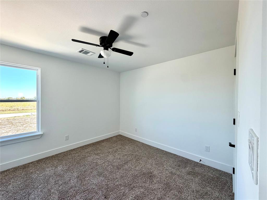 Neutral-toned carpeted flooring, white walls, and a black ceiling-mounted fan with integrated light fixture