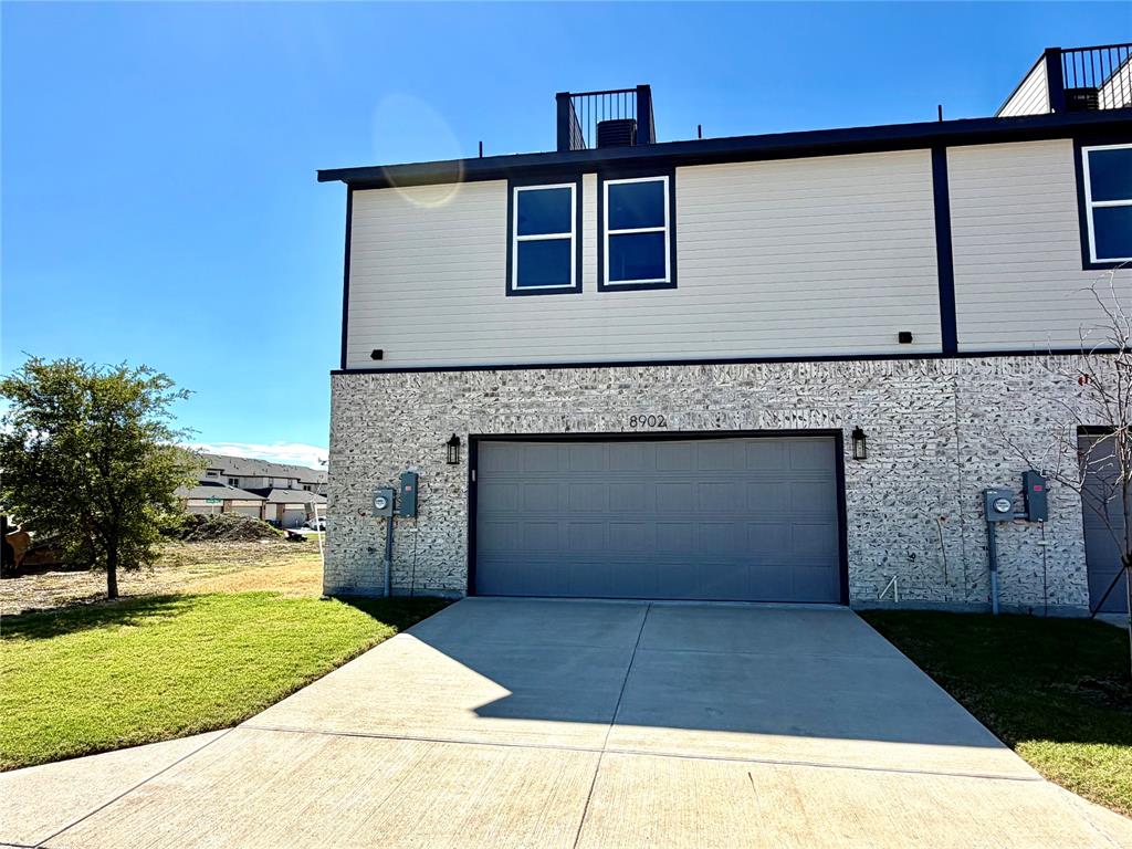 Exterior facade featuring stone veneer, horizontal siding, double-car garage, and a roof deck with metal railing