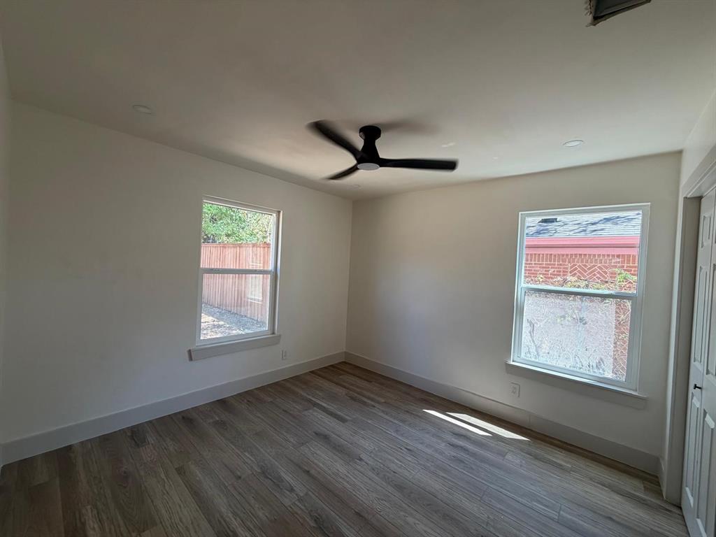Interior space featuring wood-finish flooring, dual windows with natural light, recessed lighting, and a matte black ceiling fan
