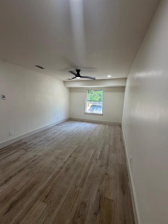 Interior space featuring wood-finish flooring, a matte black ceiling fan, recessed lighting, and a single-pane window