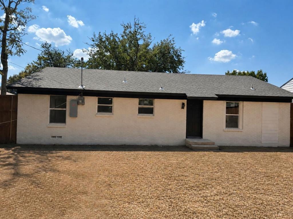 Painted brick exterior featuring a hipped roof, single-story profile, recessed entry, and fenced perimeter