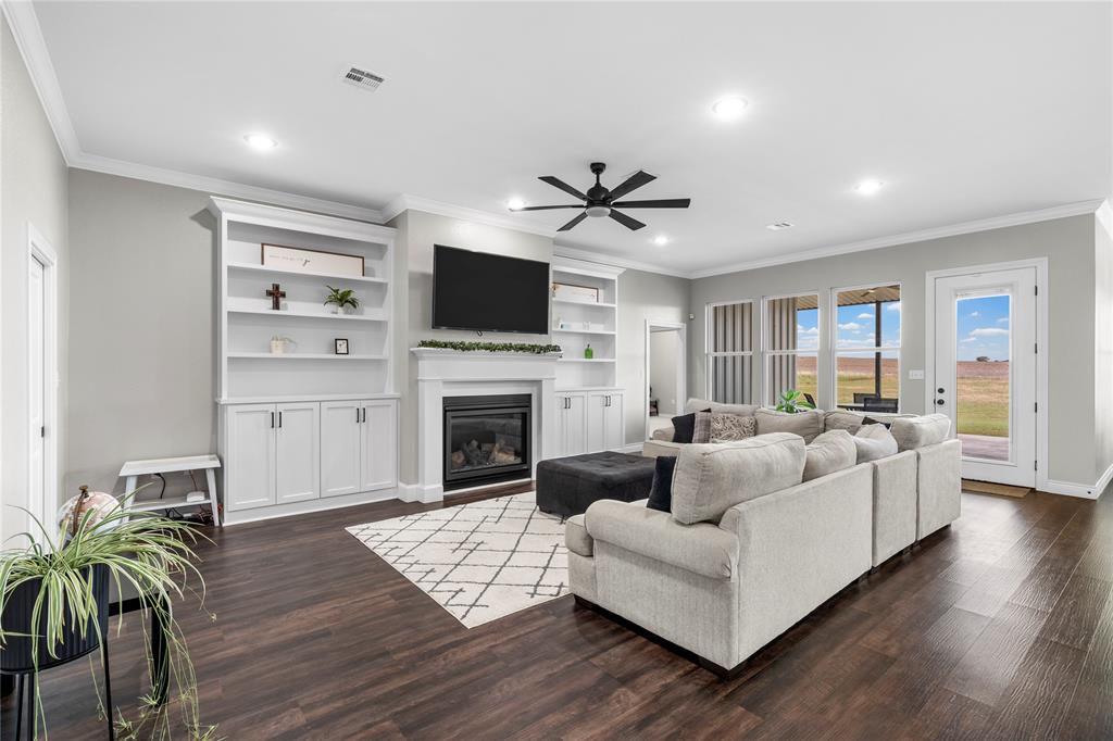 Open-concept room featuring wood-finish flooring, a fireplace with a mantel, built-in white cabinetry, recessed lighting, and a ceiling fan