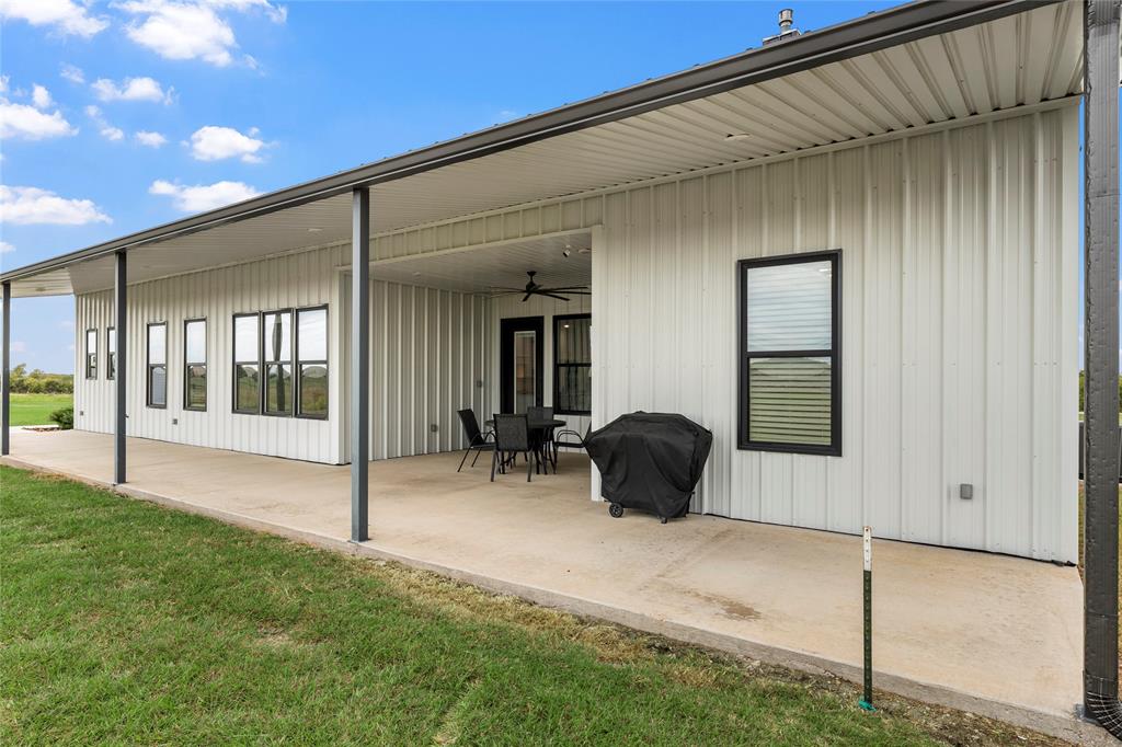 Covered concrete patio featuring metal vertical siding, black-framed windows, and a ceiling-mounted fan