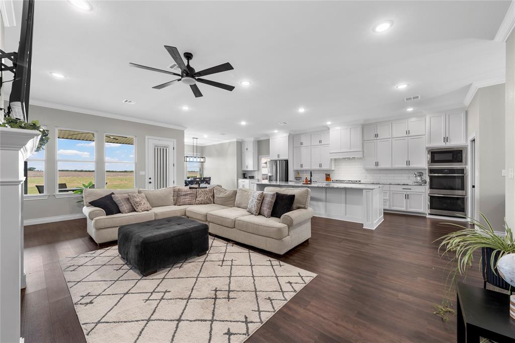 Open-concept living space featuring wood-finish flooring, white cabinetry, a large kitchen island, recessed lighting, and a ceiling fan