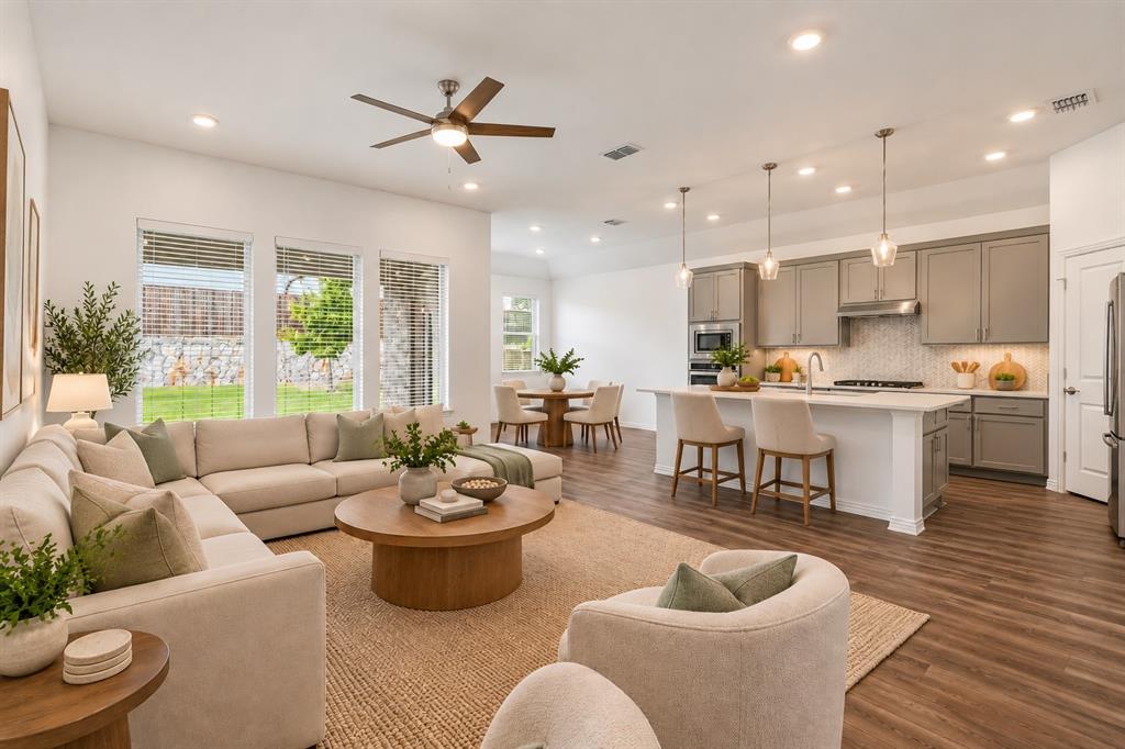 Open-concept layout featuring wood-finish flooring, recessed lighting, a center island with quartz countertops, and neutral cabinetry. Virtual photo