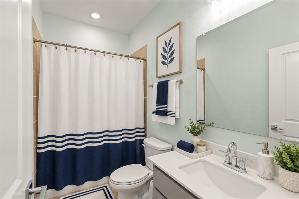 Bathroom featuring a vanity with a white countertop and rectangular undermount sink, chrome dual-handle faucet, large wall-mounted mirror, and tile surround in the shower area. Virtual photo