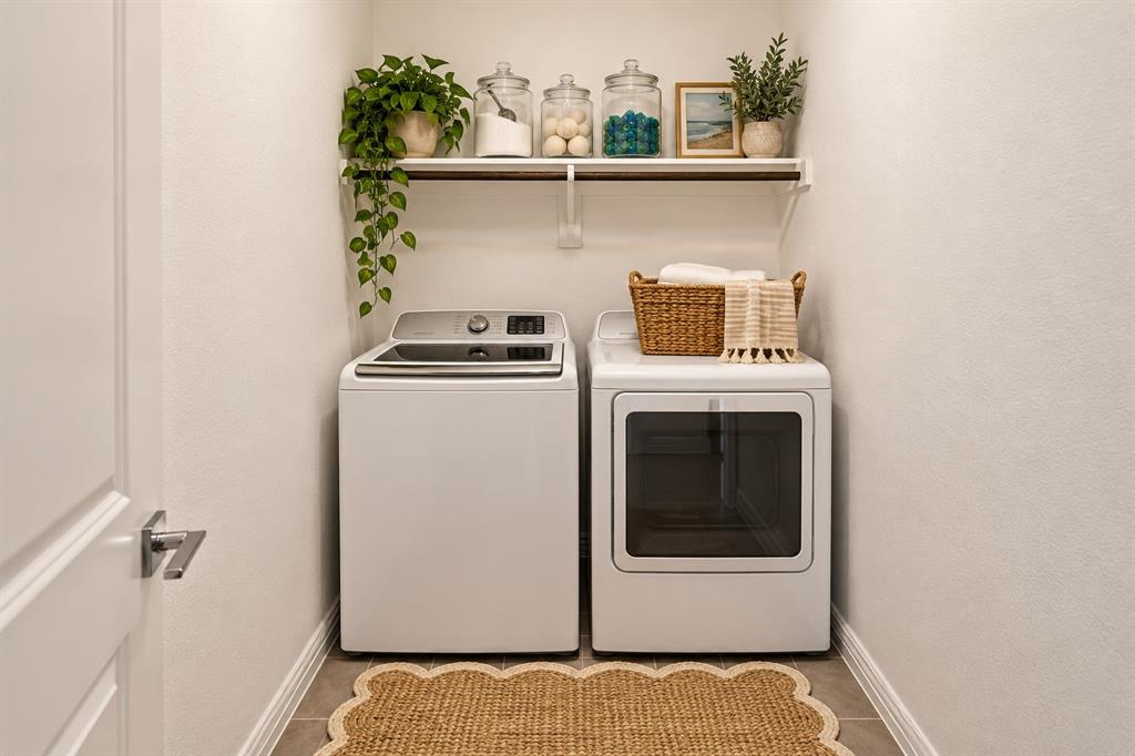 Dedicated laundry space featuring neutral ceramic tile flooring and a wall-mounted wooden shelf