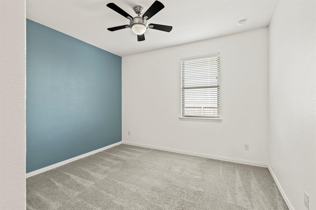 Room featuring neutral carpeting, a blue accent wall, a dual-window with horizontal blinds, and a central ceiling fan with integrated lighting