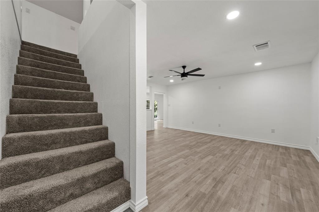 Staircase with plush carpeted steps, wood-finish flooring, recessed lighting, and a matte black ceiling fan
