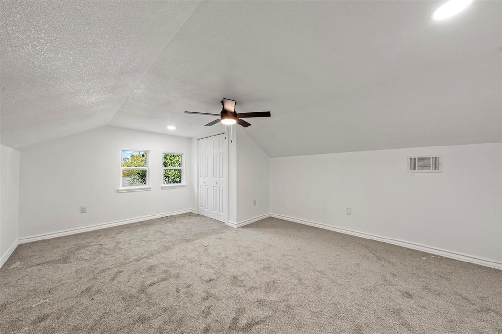 Interior room featuring vaulted ceilings, neutral wall-to-wall carpeting, recessed lighting, a ceiling fan with integrated light fixture, and two double-door closet configurations
