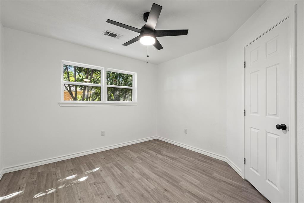 Interior space featuring wood-finish flooring, a matte black multi-blade ceiling fan with integrated lighting, and a six-panel door with matte black hardware
