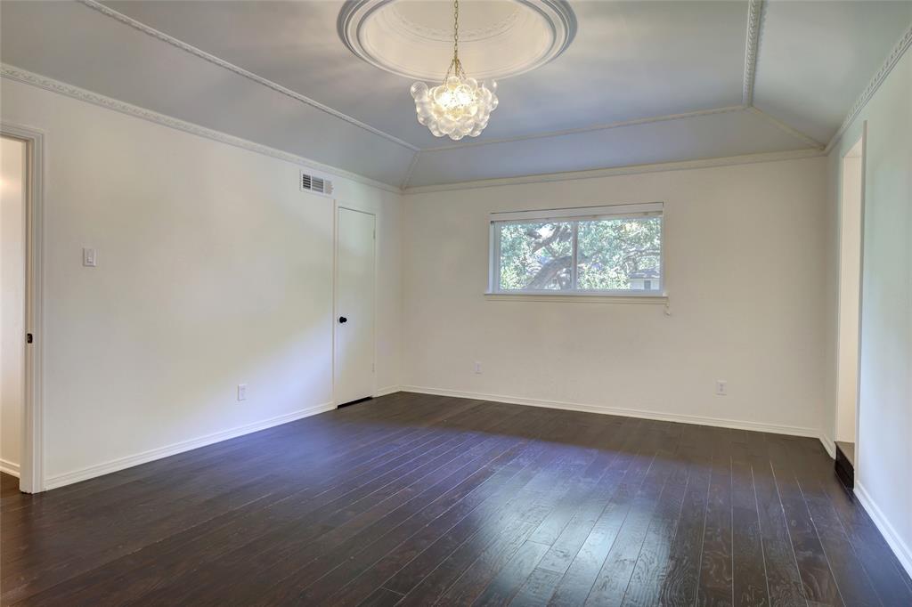 Tray ceiling featuring crown molding and an ornate central medallion, dark wood-finish flooring, and a decorative multi-sphere chandelier