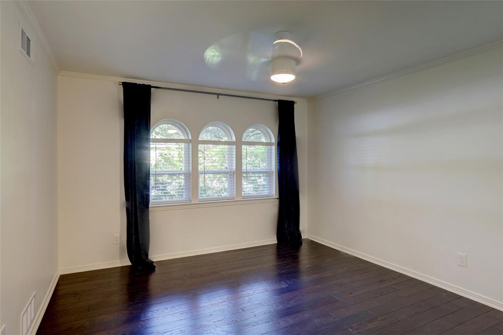 Interior space featuring dark-toned wood-finish flooring, a trio of arched windows, and a modern ceiling-mounted light fixture
