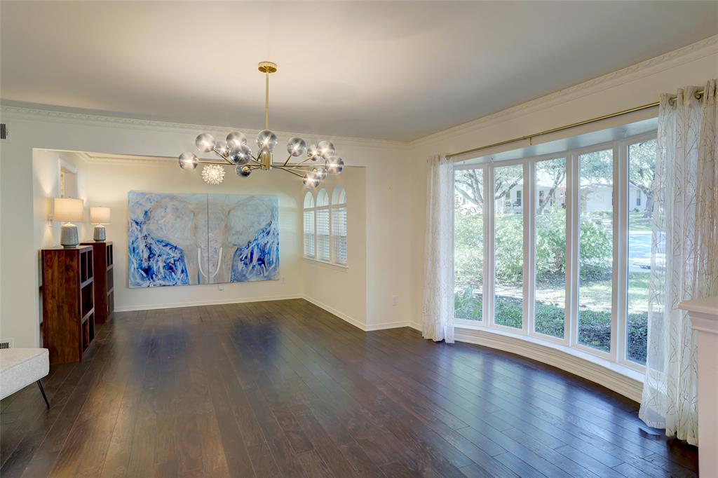 Wood-finish flooring, multi-panel bay window, contemporary multi-light metal chandelier, crown molding, and arched window detailing
