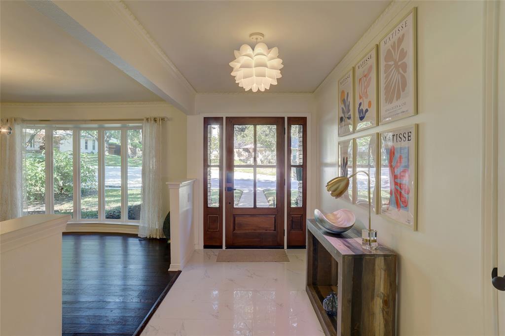 Entryway featuring a wood-framed front door with side panels, polished stone flooring, dark wood-finish flooring, and a decorative petal-style ceiling fixture