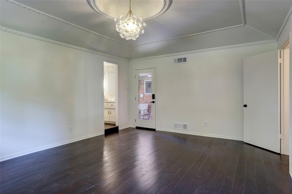 Tray ceiling featuring intricate crown molding and a decorative central medallion with a multi-globe glass pendant light, complemented by dark wood-finish flooring