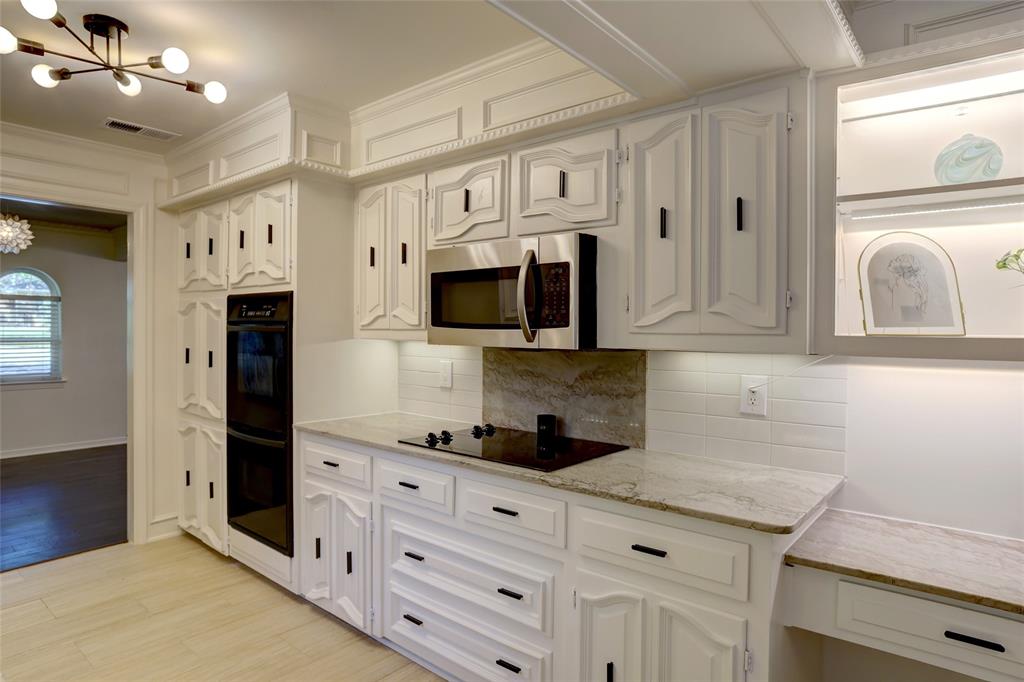 Kitchen featuring custom cabinetry with matte black hardware, stone countertops, integrated microwave, built-in wall oven, and light-toned tile flooring