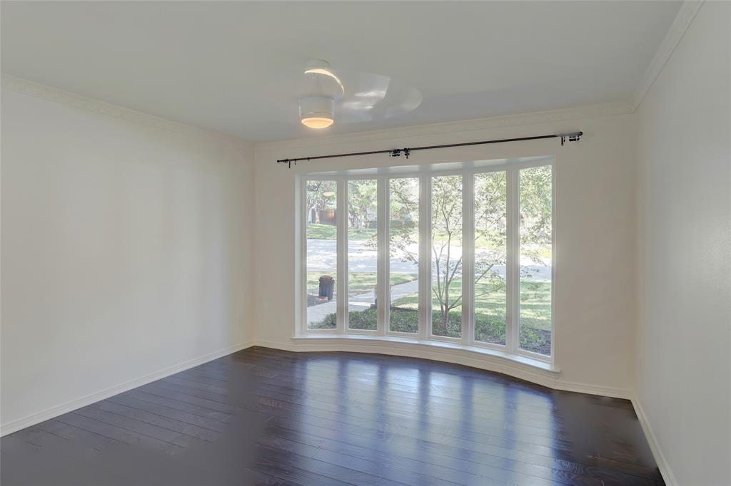 Large bay window with multiple panes, dark wood-finish flooring, and ceiling-mounted light fixture with integrated fan