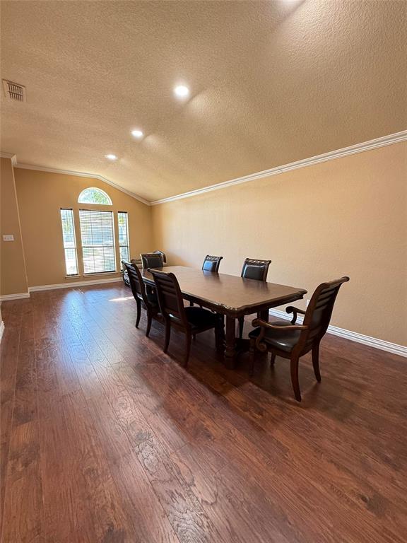 Vaulted ceiling featuring recessed lighting, crown molding, and wood-finish flooring with a multi-pane arched window