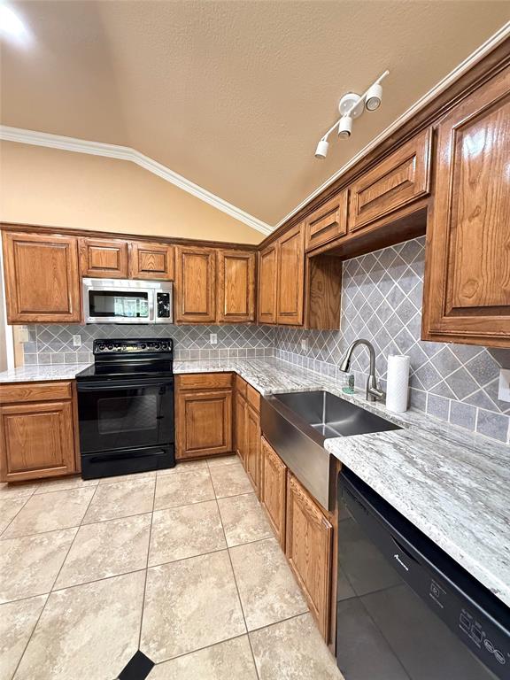 Kitchen featuring stained wood cabinetry, light-toned stone-finish countertops, stainless steel farmhouse sink, and a diamond-pattern tile backsplash