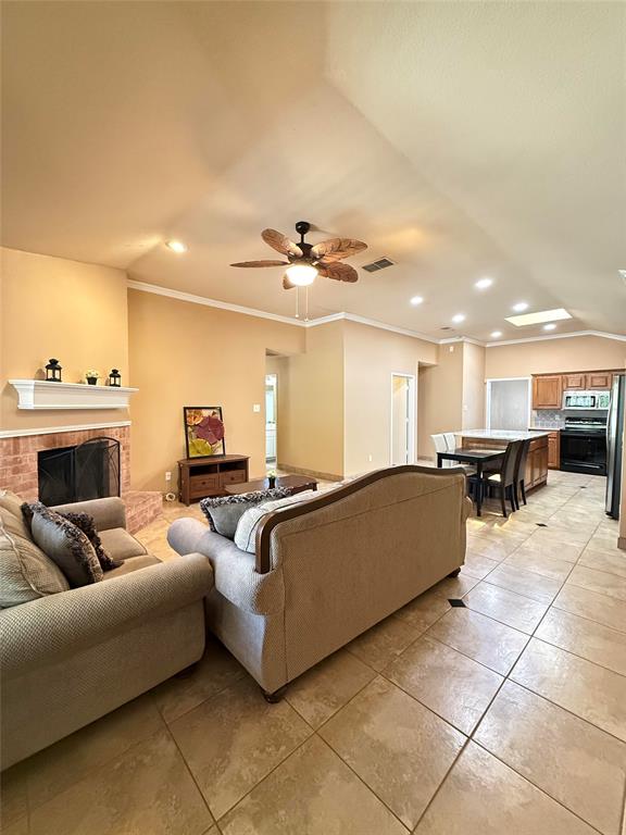 Vaulted ceilings with recessed lighting, brick fireplace with a decorative mantel, ceiling fan, and ceramic tile flooring