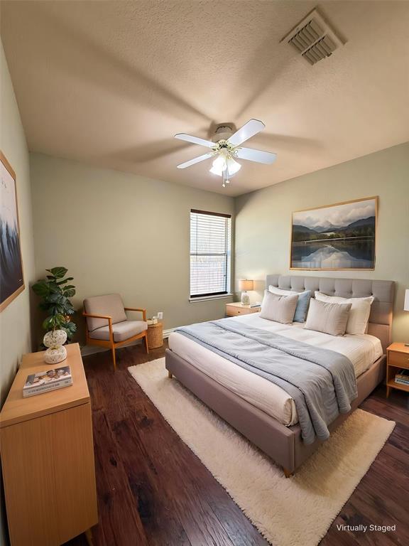 Bedroom featuring wood-finish flooring, a neutral color palette, and a multi-blade ceiling fan with integrated lighting