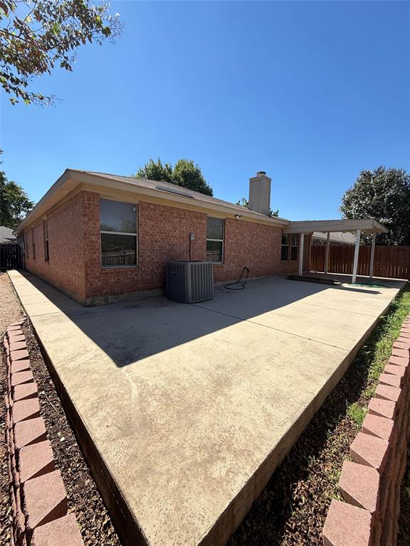 Brick exterior featuring a concrete patio, covered porch area, masonry retaining wall, and chimney