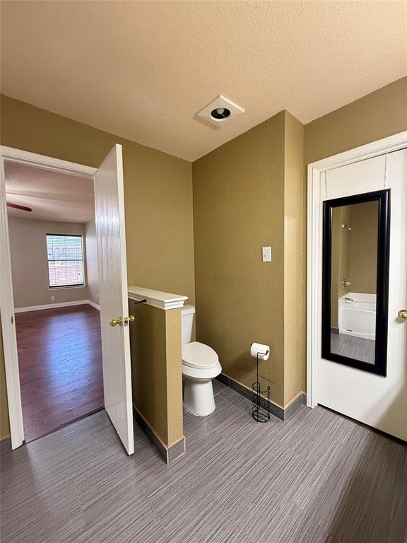 Bathroom area featuring neutral wall paint, wood-finish flooring, and an elevated half-wall partition