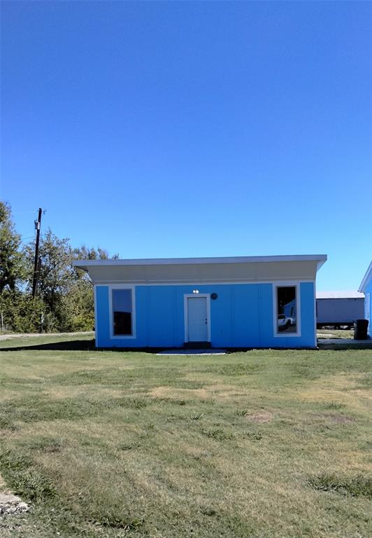 Single-story structure featuring a flat roofline, neutral-toned upper trim, exterior siding, and two rectangular windows flanking a central entrance