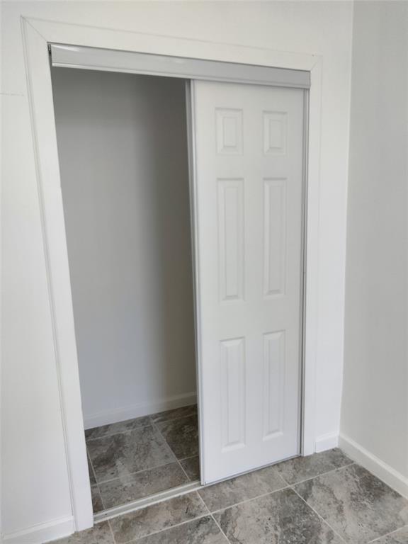Closet featuring a white six-panel sliding door and stone-finish tile flooring