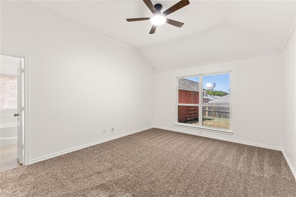Vaulted ceiling featuring a ceiling fan with integrated lighting, neutral wall-to-wall carpeting, and a double-pane window