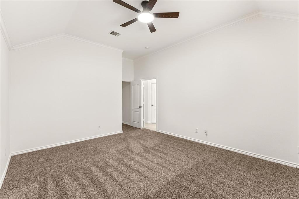 Vaulted ceilings, neutral wall tones, carpeted flooring, and an integrated ceiling fan with light fixture