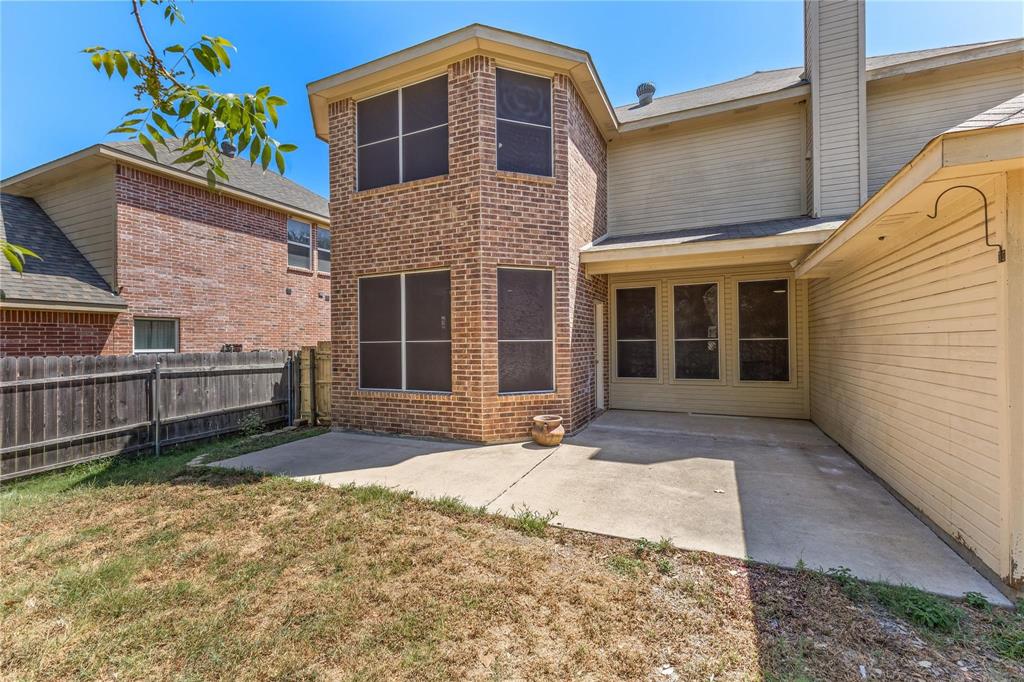 Rear exterior featuring brick masonry, horizontal siding, a concrete patio, and a wood privacy fence
