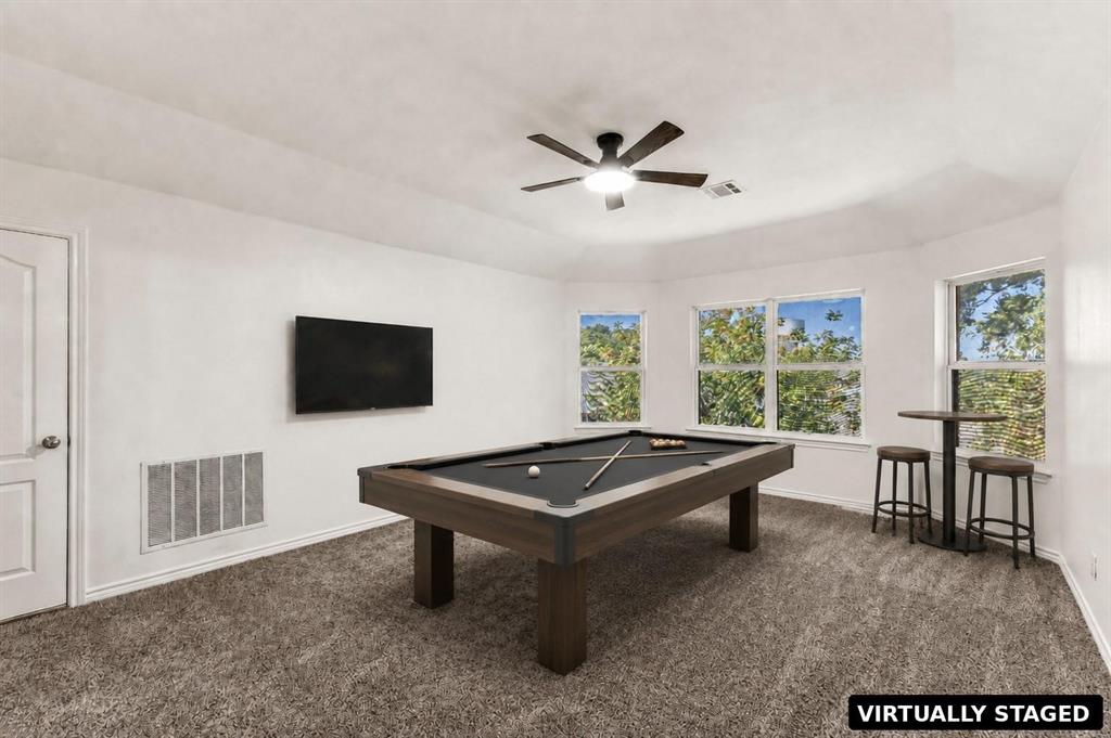 Tray ceiling featuring a central multi-blade ceiling fan with integrated lighting, expansive windows, and wall-to-wall carpeting