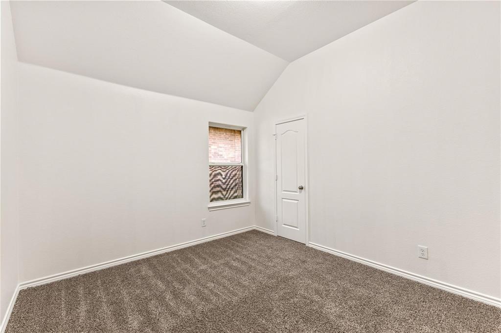 Room featuring vaulted ceilings, neutral-toned carpeting, and a single-panel interior door