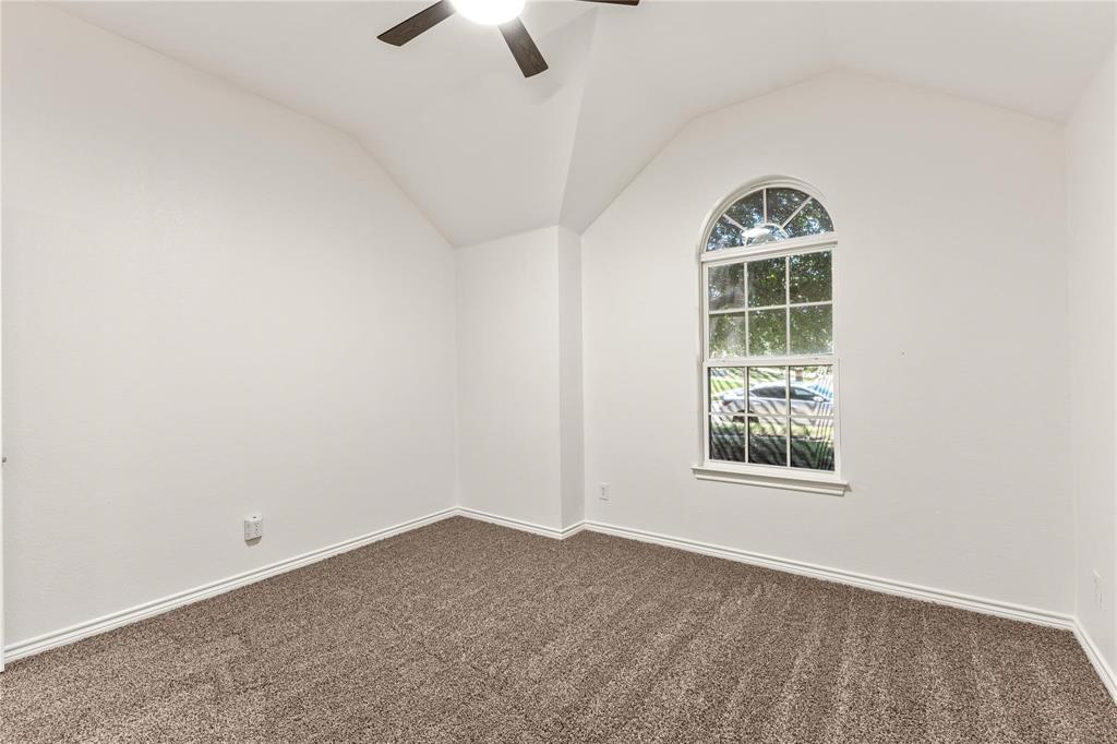 Vaulted ceiling featuring a central lighted ceiling fan, arched window, and neutral wall-to-wall carpeting