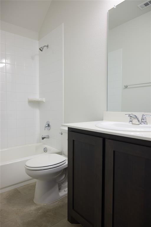 Bathroom featuring a dark wood-finish vanity, white countertop, integrated sink, and a shower-tub combination with white wall tile