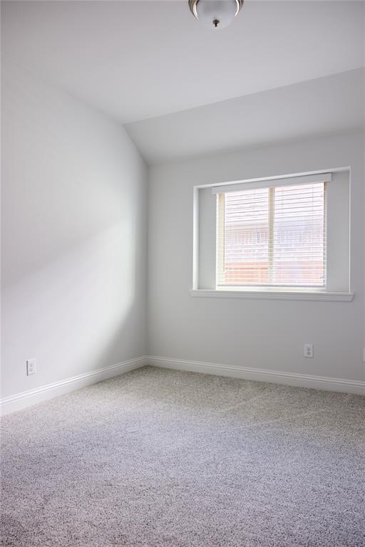 Neutral interior featuring wall-to-wall carpeting, a recessed window with horizontal blinds, and a central ceiling-mounted light fixture