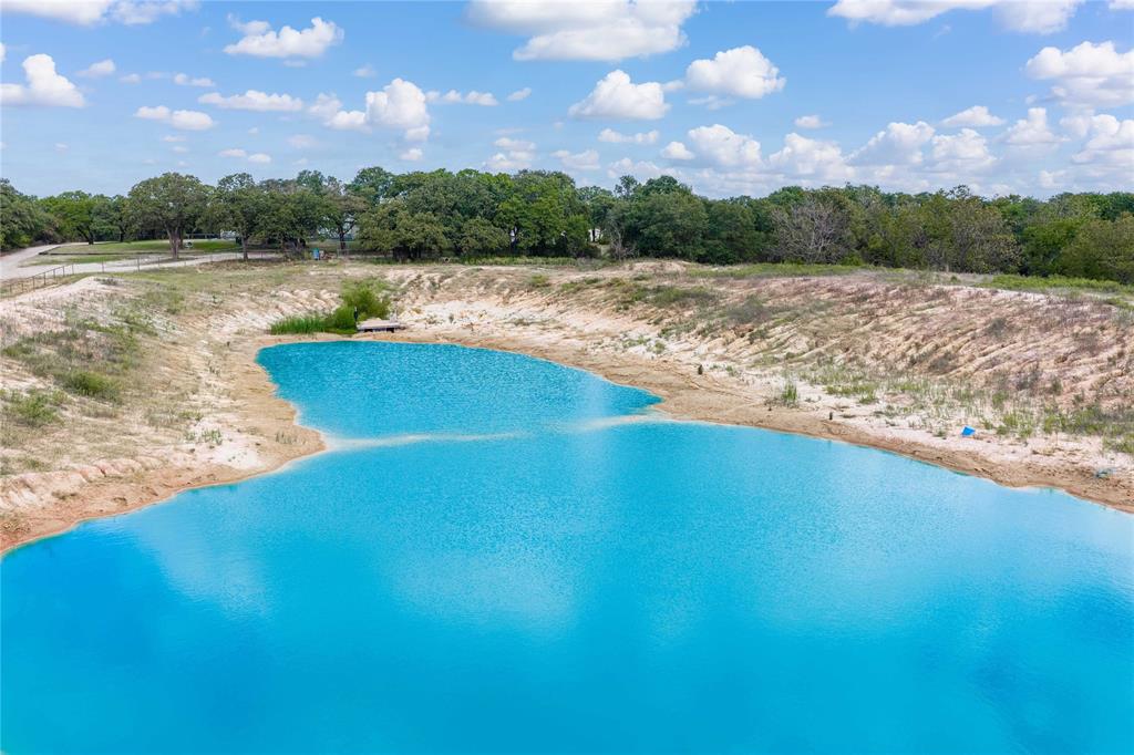 Expansive pond featuring natural shoreline, sandy banks, and surrounding mature trees