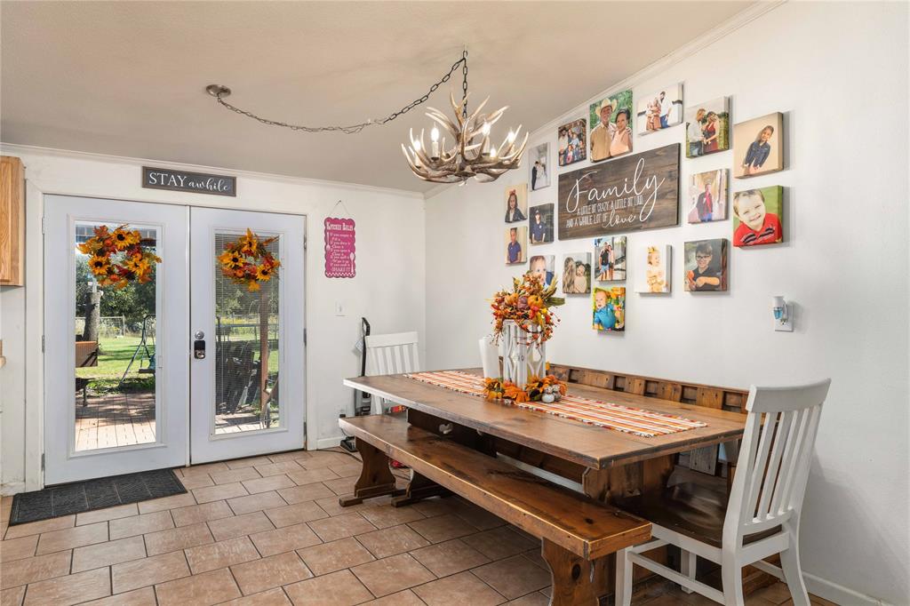 Double glass-paneled exterior doors featuring integrated blinds, ceramic tile flooring, and a decorative antler-style chandelier