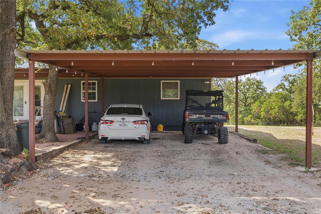 Metal-frame carport with integrated lighting, finished exterior siding, and a gravel driveway surface