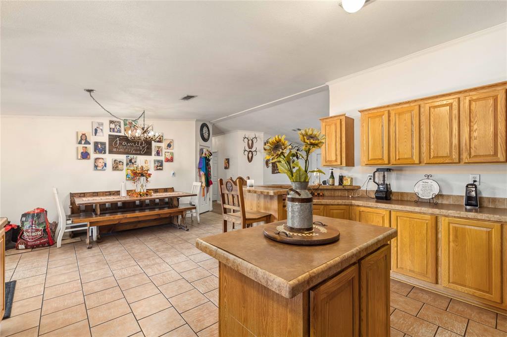 Kitchen featuring wood cabinetry, a center island with a stone-finish countertop, and tile flooring